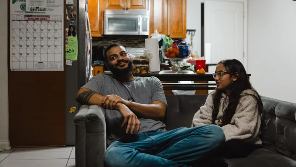 Christopher Santiago, 38, hangs out at home in Alsip, Ill., with one of his three children, 9-year-old Calliope. He says Cook County's basic income program has let him provide more for his kids. Taylor Glascock for NPR